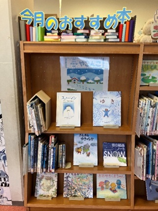 こどもとしょしつの2月の展示。雪の結晶や雪だるまなどの絵本が複数冊表紙が見えるよう並んでいる