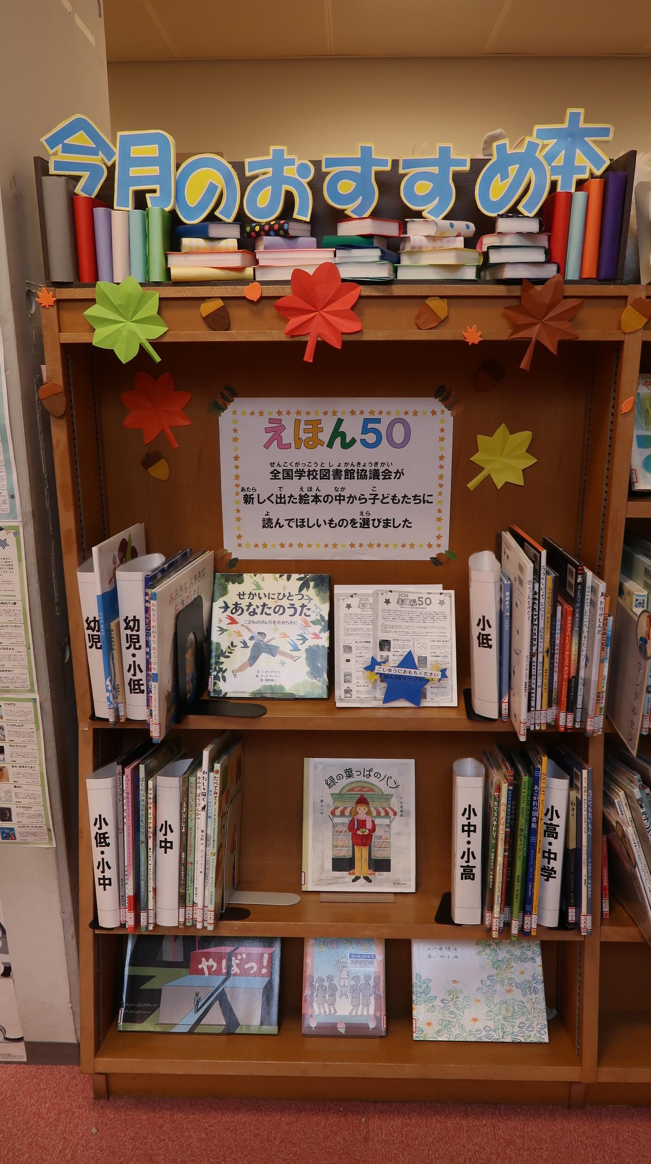10月のおすすめ本。こどもとしょしつの今月のおすすめ本コーナーに、対象学年別に棚にサインを設けて展示された絵本が並んでいる。
